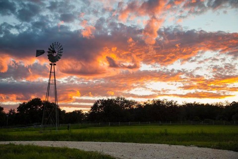 Orange clouds at sunset with windmill and freshly surfaced road to the house.