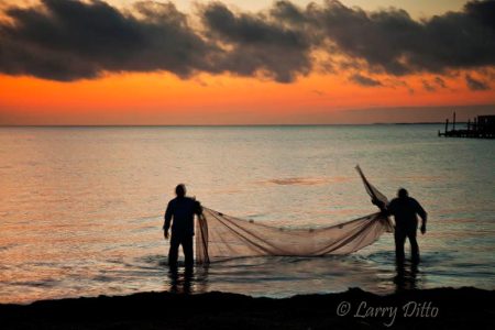 Fishermen with net at sunrise.