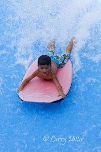 Boogie Bahn! Little Max Lerma of Los Fresnos, Texas boogie boarding on a jet of water that looks and feels like the front of a big wave. Waterpark attendants and parents are standing nearby to insure Max's ride is a safe one.