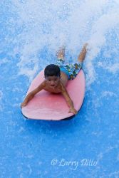 Boogie Bahn! Little Max Lerma of Los Fresnos, Texas boogie boarding on a jet of water that looks and feels like the front of a big wave. Waterpark attendants and parents are standing nearby to insure Max's ride is a safe one.